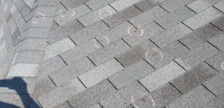 Asphalt shingles with chalk circles marking hail impacts