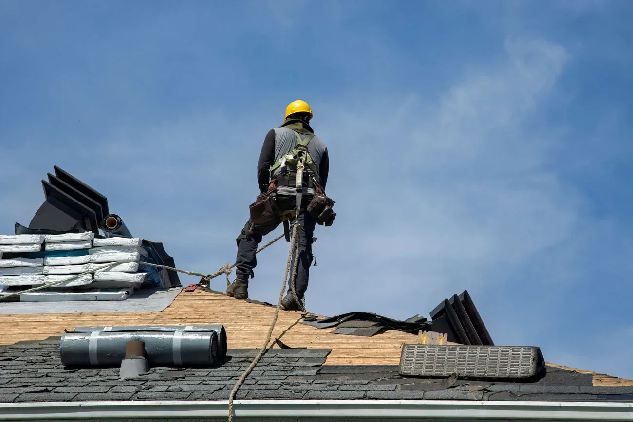 Roofer on a roof with shingle bundles staged