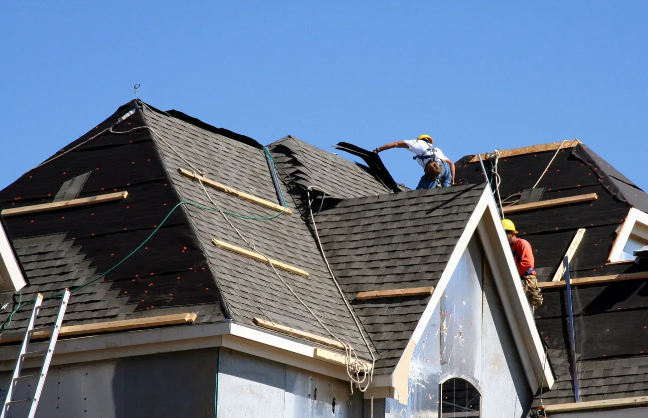 Roofing crew tearing off old shingles on a home