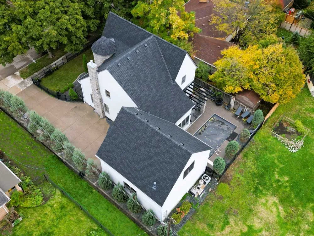 Aerial view of a completed residential roofing project with new dark shingles