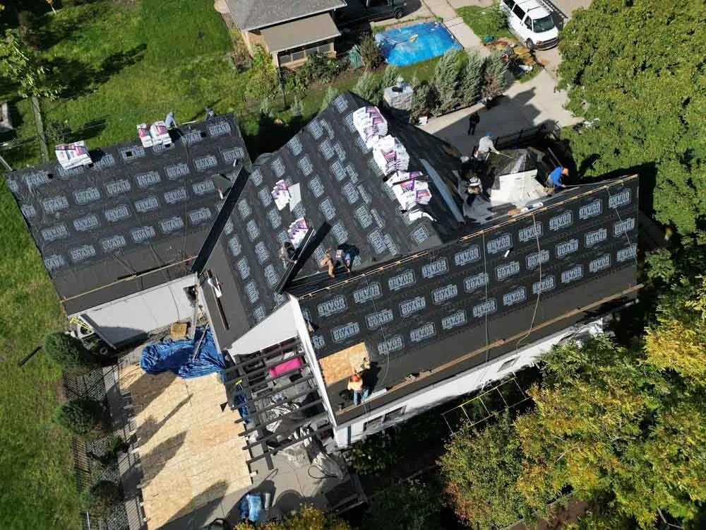 Overhead view of a roof replacement in progress with old shingles torn off and underlayment down