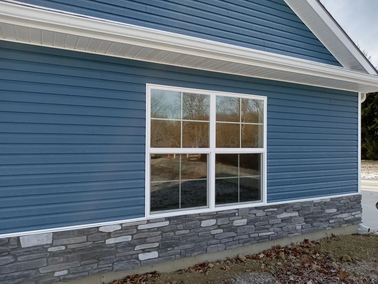 Blue siding with a new white window and stone base