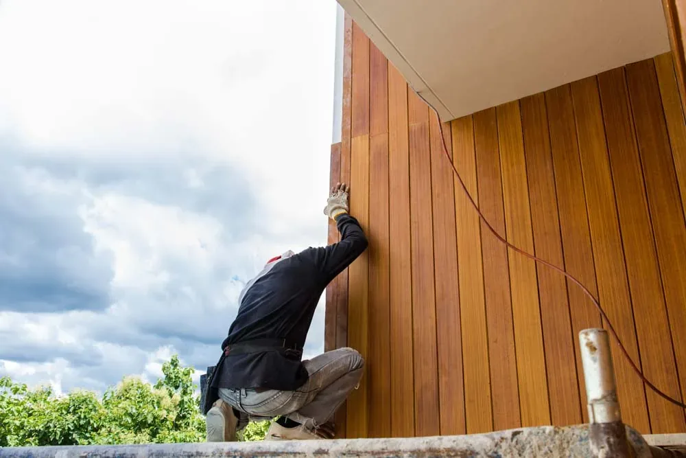 Installer fitting fiber cement board siding on a home