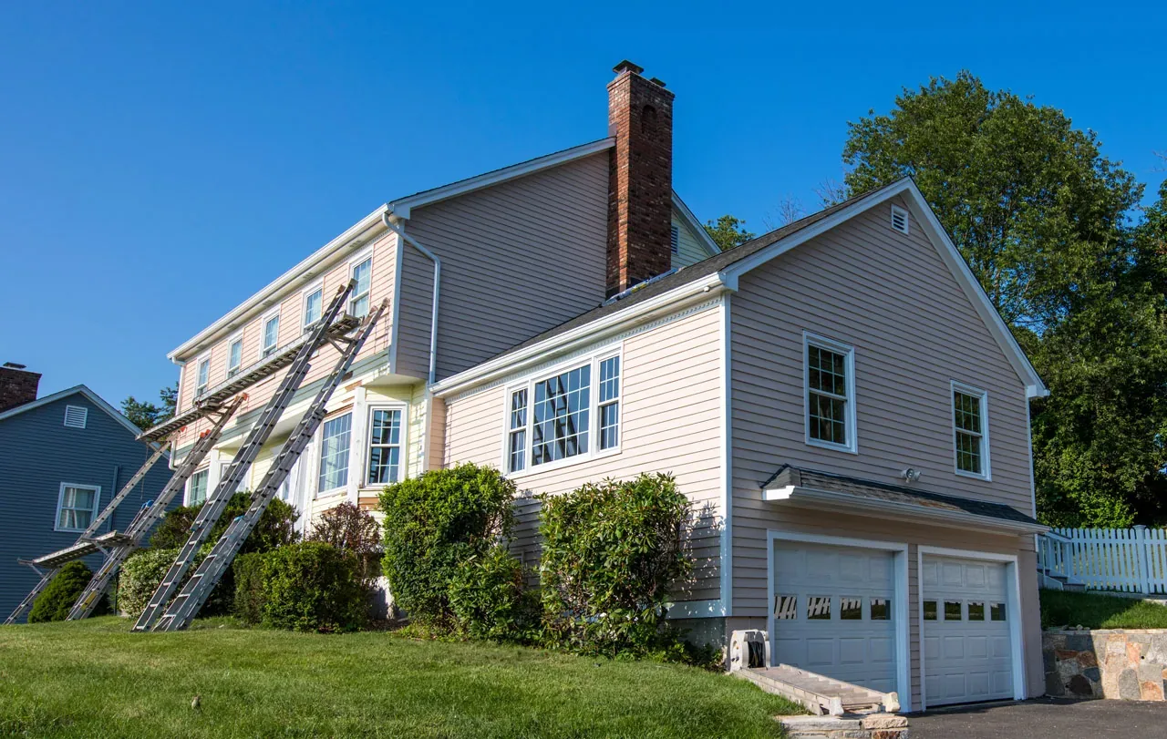 Two-story home mid-project with new siding going on and ladders set up