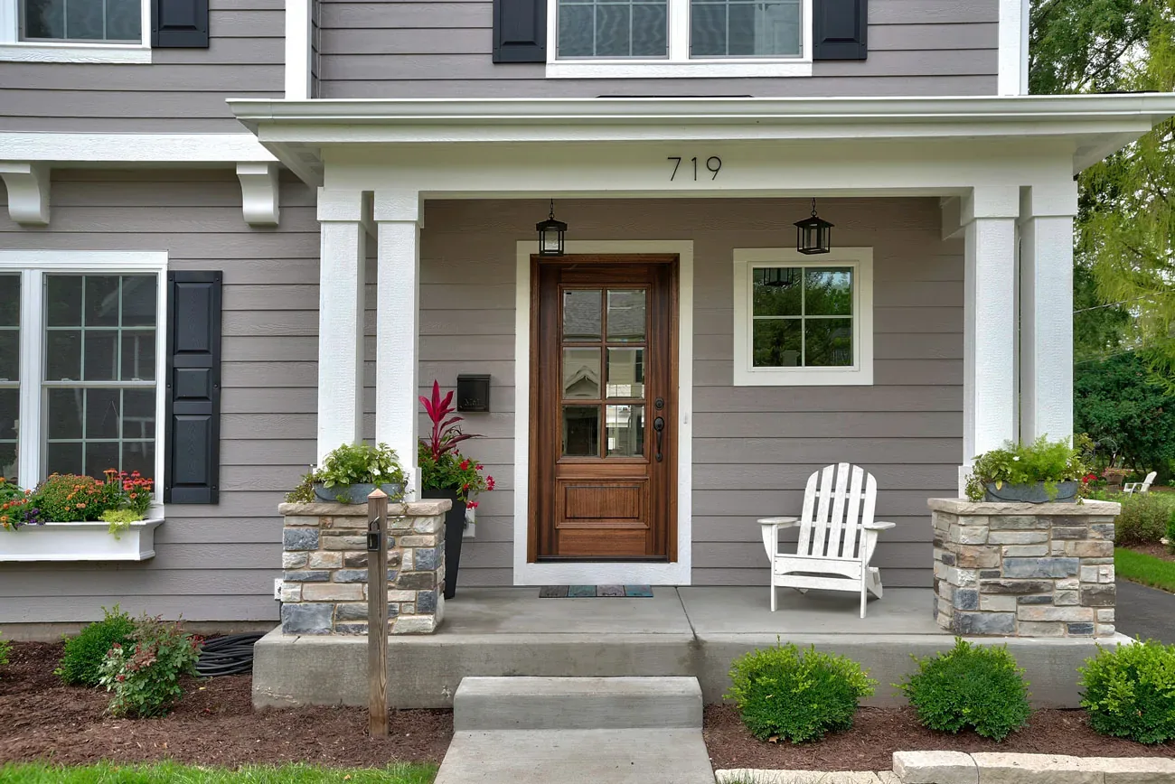 Taupe two-story home with a covered front porch and new siding