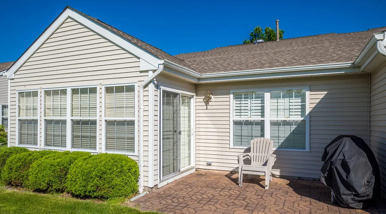 Beige vinyl siding on a ranch home with a paver patio